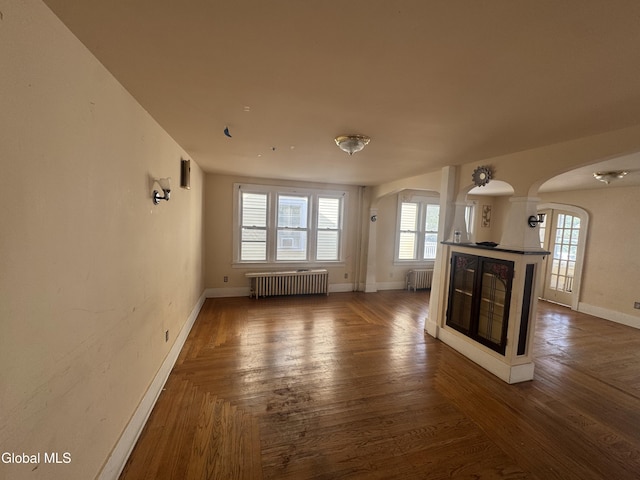 261 Altamont Ave, Schenectady, NY 12304 - unfurnished living room with arched walkways, radiator, and a tiled fireplace