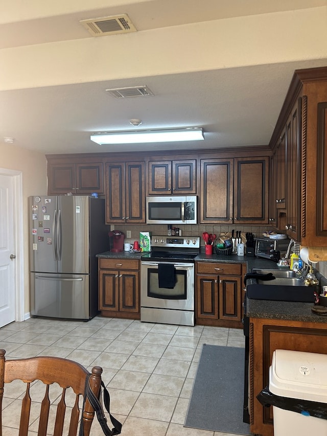 5175 Calvary Cir, Valdosta, GA 31605 - kitchen featuring stainless steel appliances, dark countertops, light tile patterned flooring, and dark brown cabinets