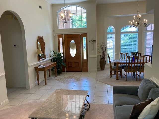 tiled foyer entrance with crown molding, plenty of natural light, a chandelier, and a high ceiling