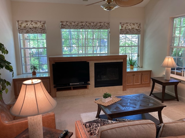 carpeted living room with a tile fireplace, ceiling fan, and plenty of natural light