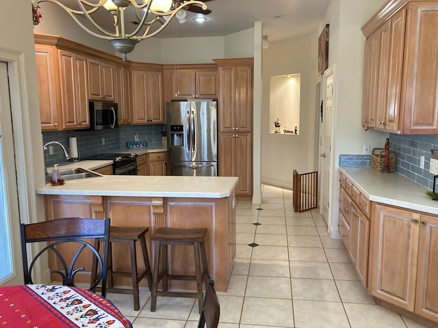 kitchen with an inviting chandelier, sink, decorative backsplash, a kitchen bar, and stainless steel appliances