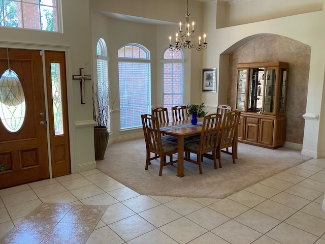 carpeted dining area with a notable chandelier and a high ceiling