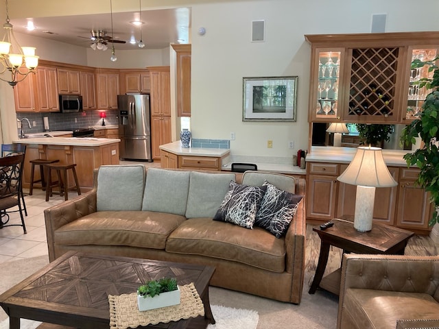 tiled living room with ceiling fan with notable chandelier and sink