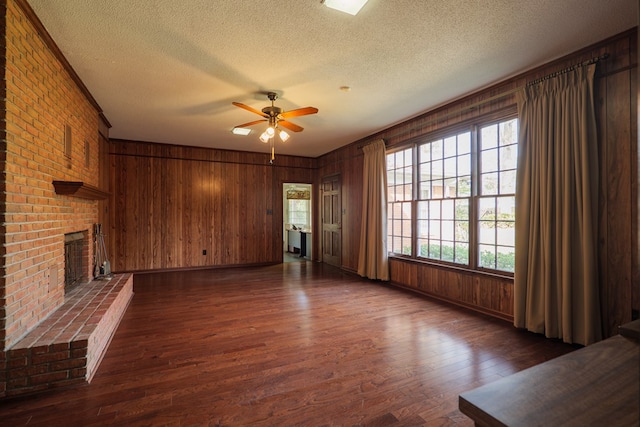 unfurnished living room featuring ceiling fan, a fireplace, dark wood-type flooring, and a textured ceiling