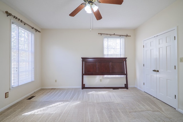 unfurnished bedroom featuring light carpet, a textured ceiling, a closet, and ceiling fan