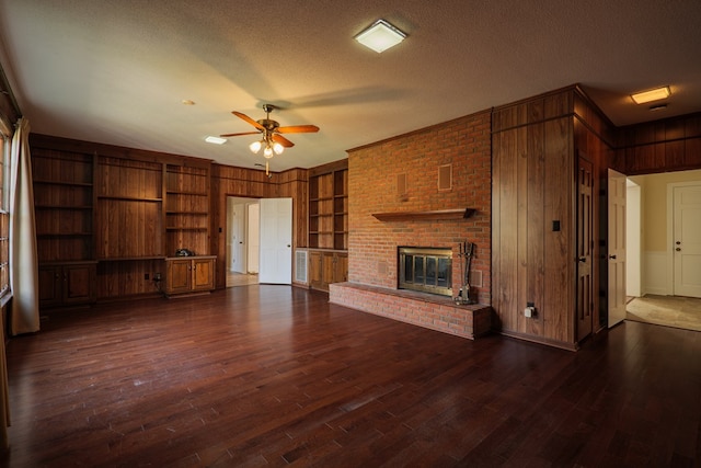 unfurnished living room with dark hardwood / wood-style floors, wood walls, a textured ceiling, and built in shelves