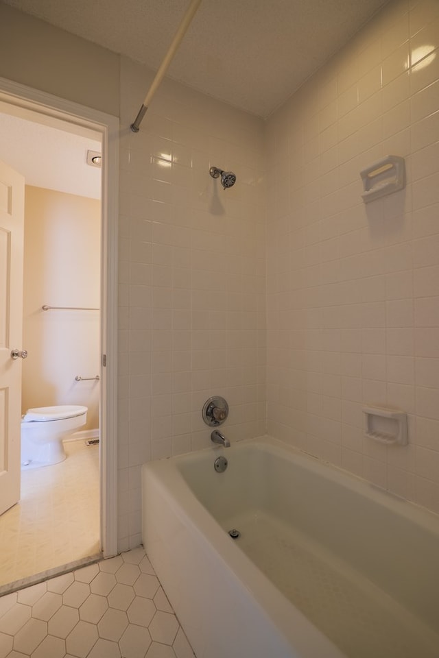 bathroom featuring tile patterned floors, tiled shower / bath combo, and toilet