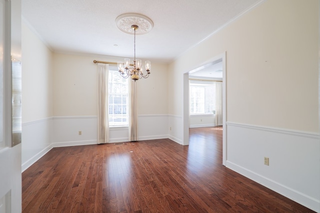 unfurnished dining area featuring a textured ceiling, a notable chandelier, ornamental molding, and dark wood-type flooring