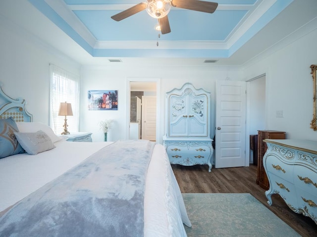 bedroom with dark wood-type flooring, a raised ceiling, and visible vents