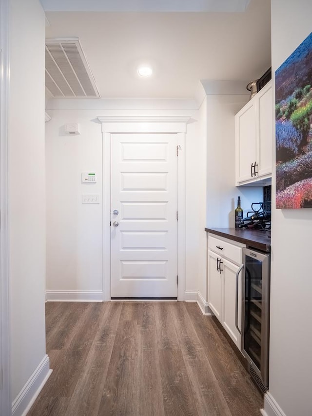 bar with wine cooler, a dry bar, visible vents, dark wood-type flooring, and baseboards