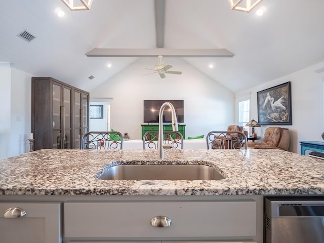 kitchen featuring visible vents, open floor plan, vaulted ceiling with beams, light stone countertops, and a sink