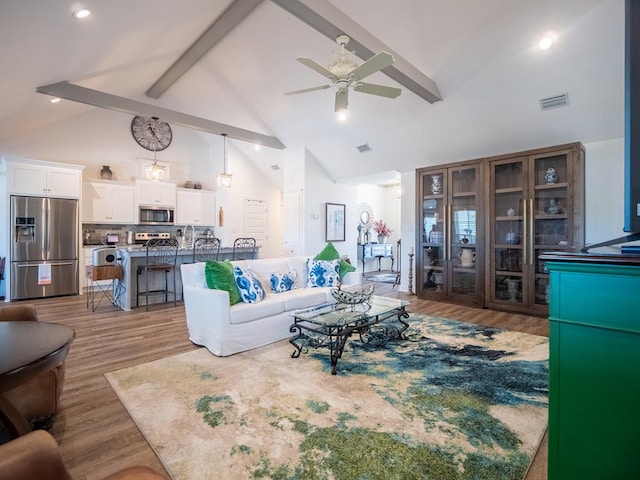 living room featuring visible vents, beamed ceiling, wood finished floors, and a ceiling fan