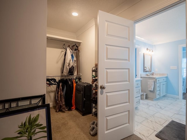 walk in closet featuring marble finish floor and a sink