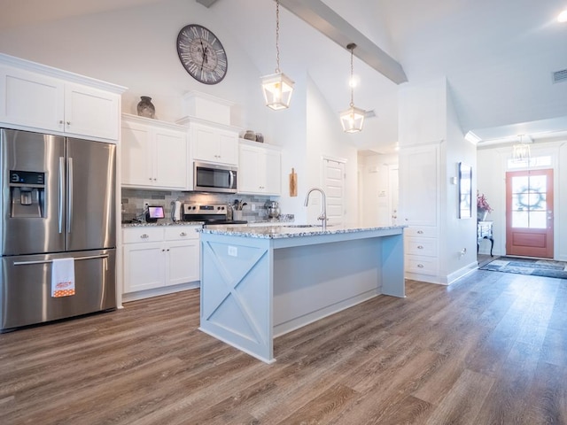 kitchen with appliances with stainless steel finishes, white cabinets, a sink, and wood finished floors