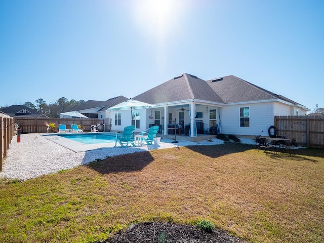 rear view of house with a fenced backyard, a ceiling fan, a lawn, and a patio