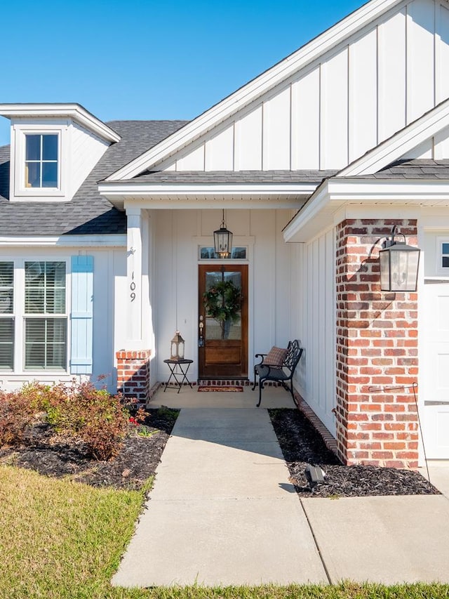 property entrance with roof with shingles, brick siding, and board and batten siding