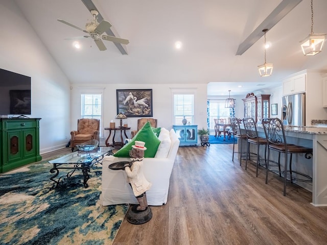 living room featuring vaulted ceiling with beams, ceiling fan, baseboards, and wood finished floors