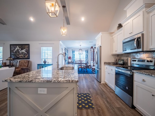 kitchen featuring stainless steel appliances, a sink, white cabinets, light stone countertops, and an island with sink