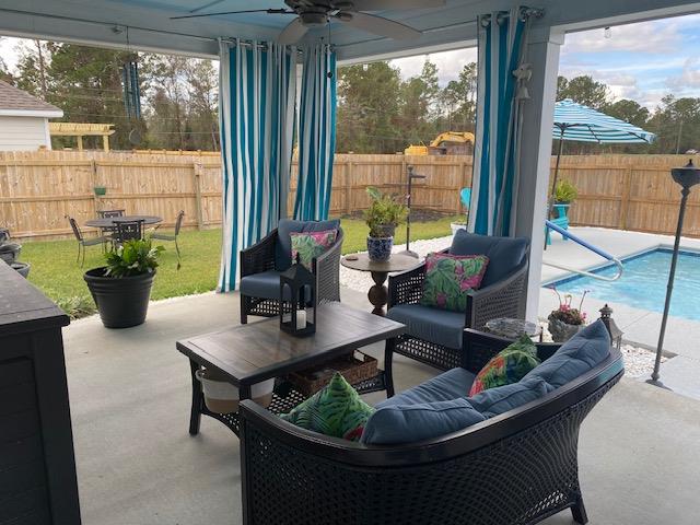 view of patio / terrace with ceiling fan, a fenced backyard, an outdoor living space, and a fenced in pool