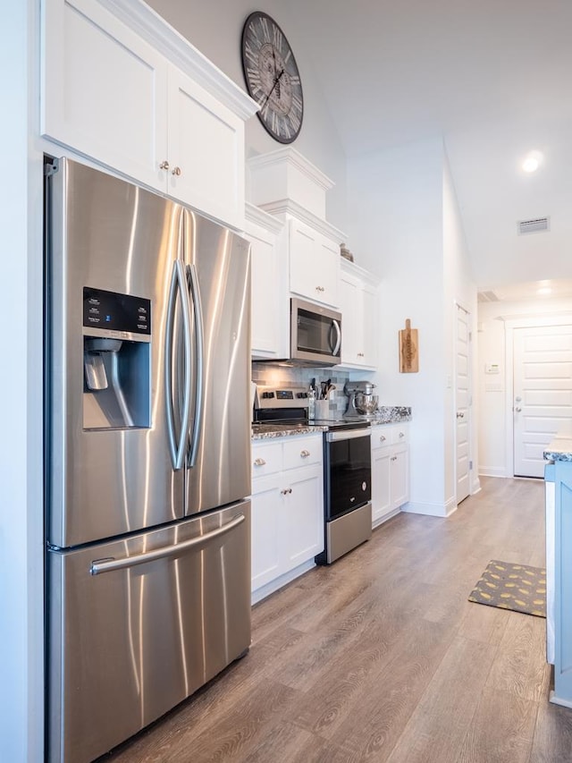 kitchen with stainless steel appliances, white cabinets, visible vents, and light wood-style flooring