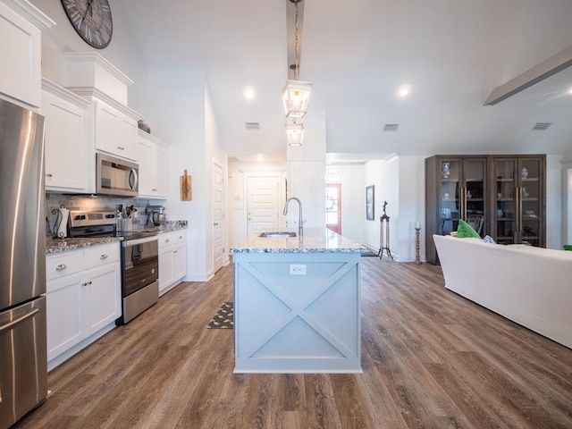 kitchen featuring dark wood finished floors, tasteful backsplash, appliances with stainless steel finishes, white cabinets, and a sink