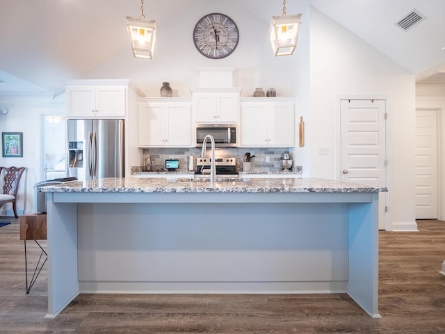 kitchen featuring visible vents, appliances with stainless steel finishes, white cabinets, a sink, and a large island with sink