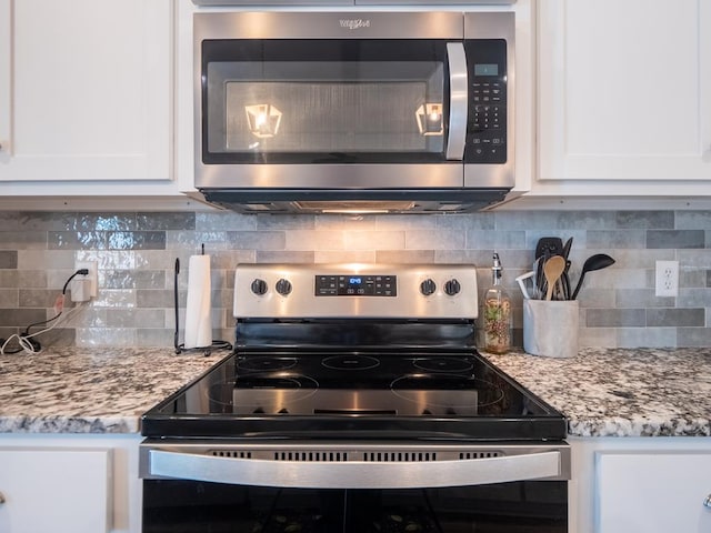 kitchen with stainless steel appliances, white cabinets, decorative backsplash, and light stone countertops