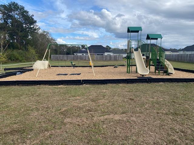 community play area featuring fence and a lawn