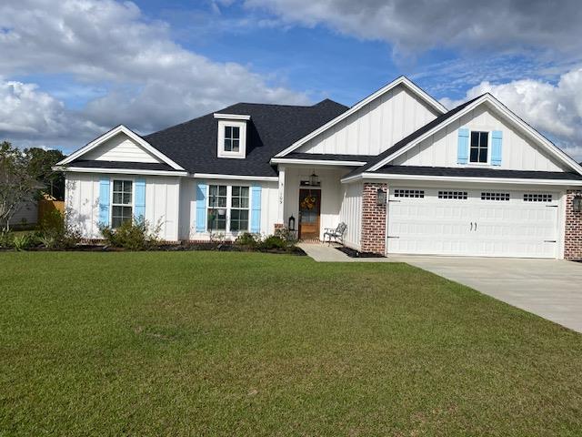 view of front of property with board and batten siding, brick siding, concrete driveway, and a front yard