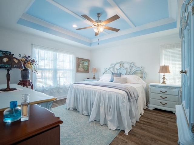 bedroom featuring dark wood-style floors, ceiling fan, a tray ceiling, and crown molding