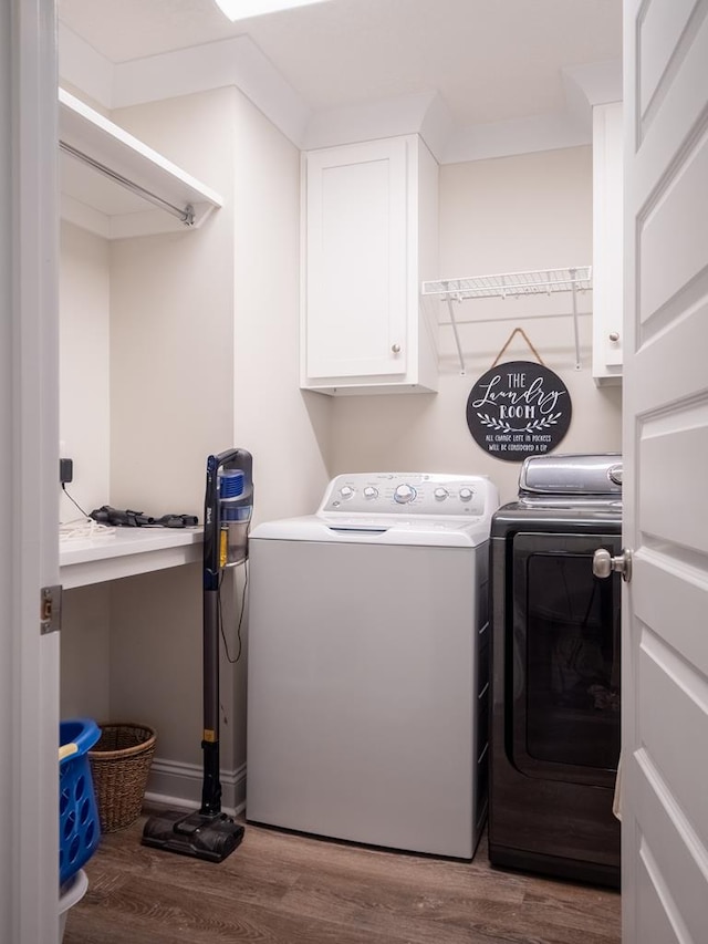 laundry room featuring washer and dryer, cabinet space, and wood finished floors