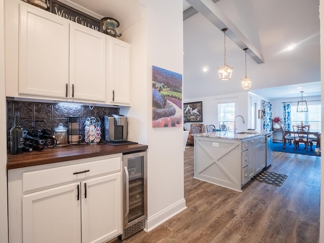 kitchen featuring wine cooler, dark wood-style flooring, a sink, wooden counters, and backsplash