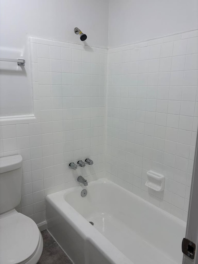 bathroom featuring tile patterned flooring, tile walls, toilet, and shower / washtub combination