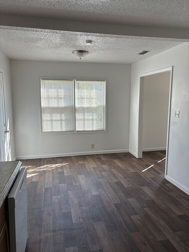 spare room featuring a textured ceiling and dark hardwood / wood-style floors