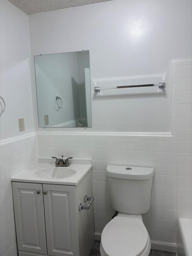 bathroom with tile walls, toilet, and vanity