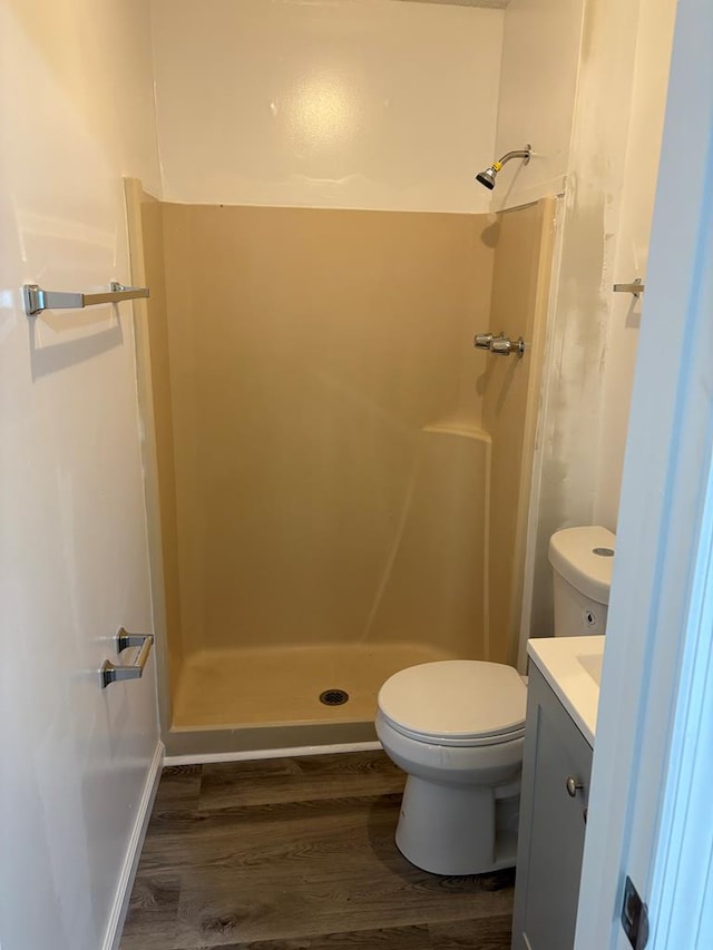 bathroom with wood-type flooring, toilet, vanity, and walk in shower