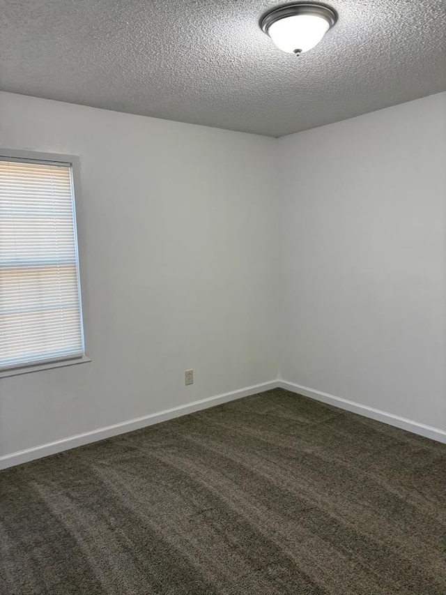 empty room featuring a textured ceiling and dark colored carpet