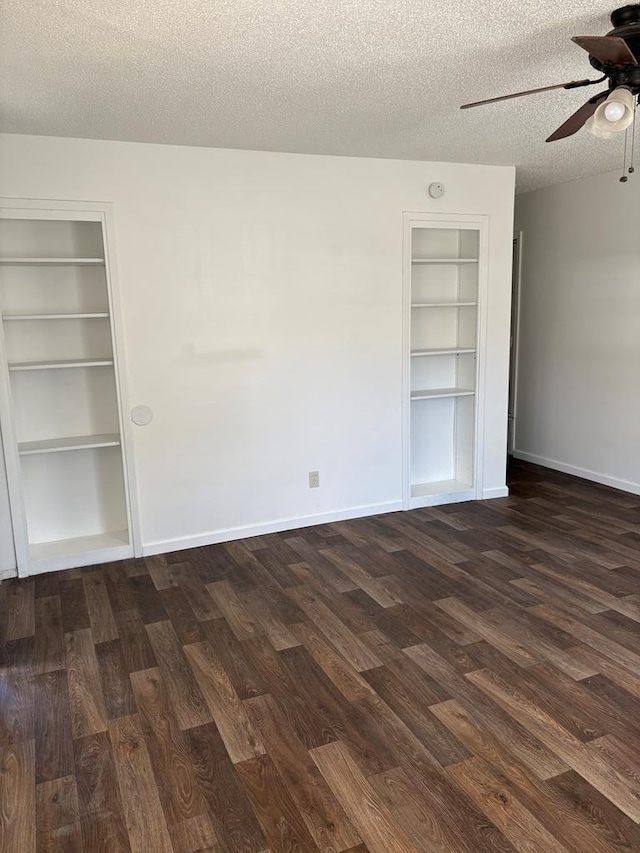 spare room with a textured ceiling, ceiling fan, dark hardwood / wood-style flooring, and built in features