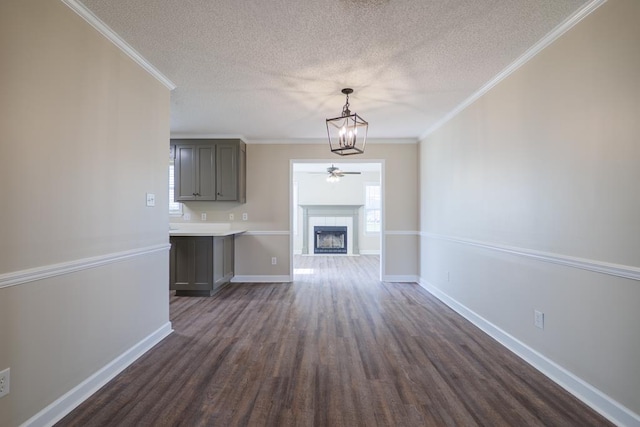 unfurnished living room with baseboards, dark wood-style floors, crown molding, a textured ceiling, and a fireplace