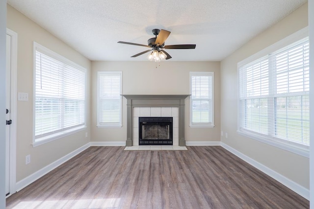 unfurnished living room featuring a textured ceiling, a fireplace, wood finished floors, and baseboards