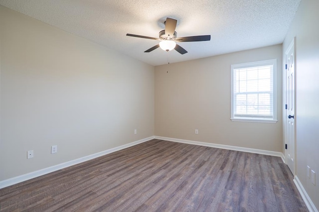 empty room featuring a textured ceiling, baseboards, and dark wood-style flooring