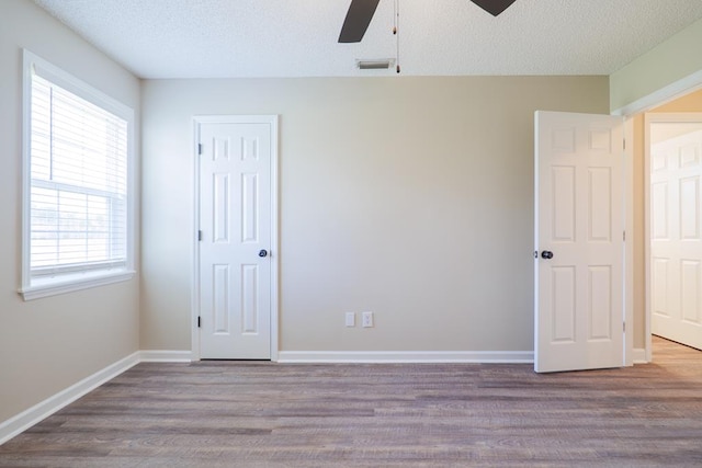 unfurnished bedroom with baseboards, visible vents, a textured ceiling, and light wood finished floors