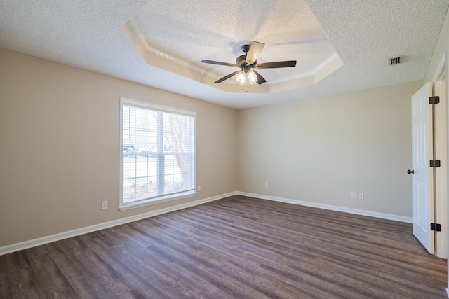 unfurnished room featuring visible vents, dark wood finished floors, baseboards, a tray ceiling, and a textured ceiling