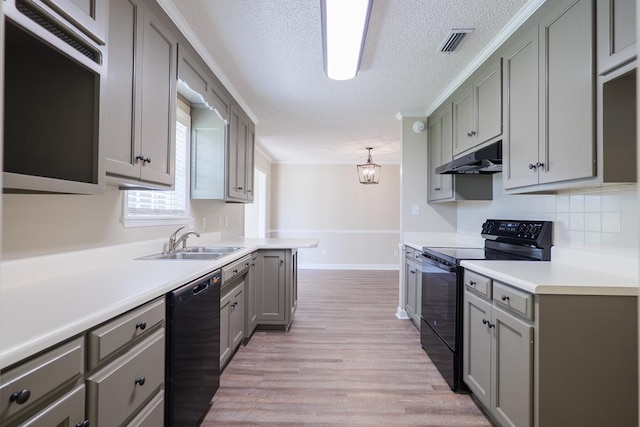 kitchen with black appliances, under cabinet range hood, light countertops, and a sink