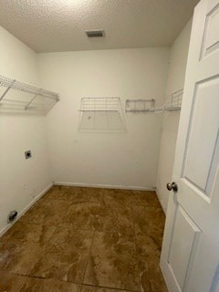interior space with laundry area, a textured ceiling, hookup for an electric dryer, and visible vents