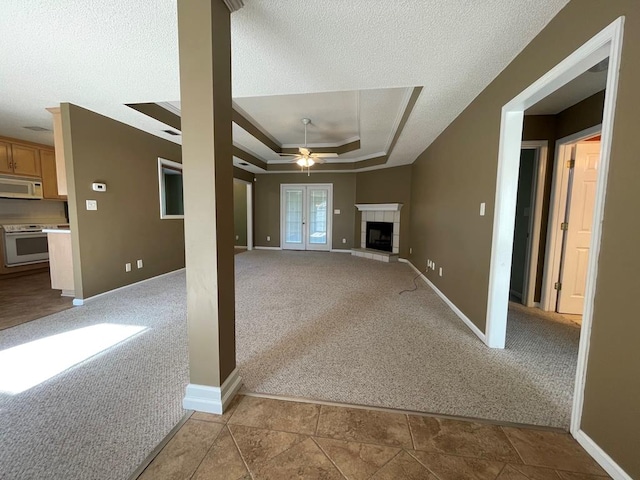 4331 Summerlin Dr, Valdosta, GA 31605 - unfurnished living room with baseboards, a raised ceiling, a tile fireplace, a ceiling fan, and carpet