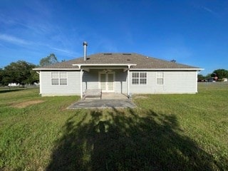 rear view of property featuring a lawn and a patio area