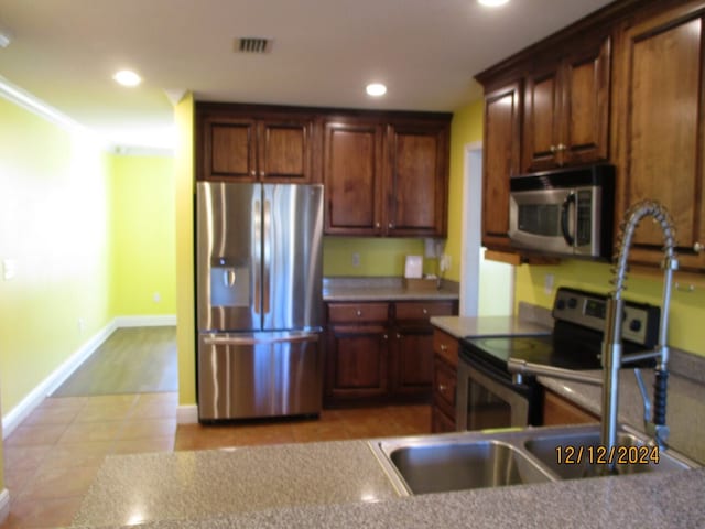 kitchen with sink, ornamental molding, stainless steel appliances, and light tile patterned floors