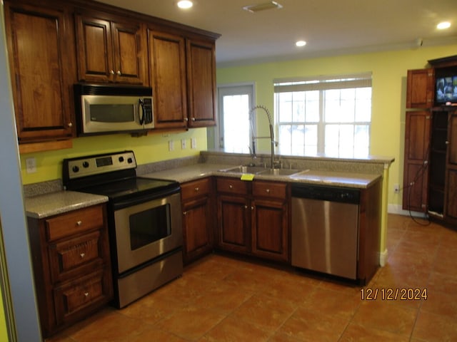 kitchen featuring kitchen peninsula, appliances with stainless steel finishes, tile patterned floors, and sink