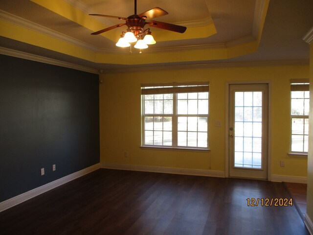 unfurnished room with dark hardwood / wood-style flooring, a tray ceiling, and crown molding